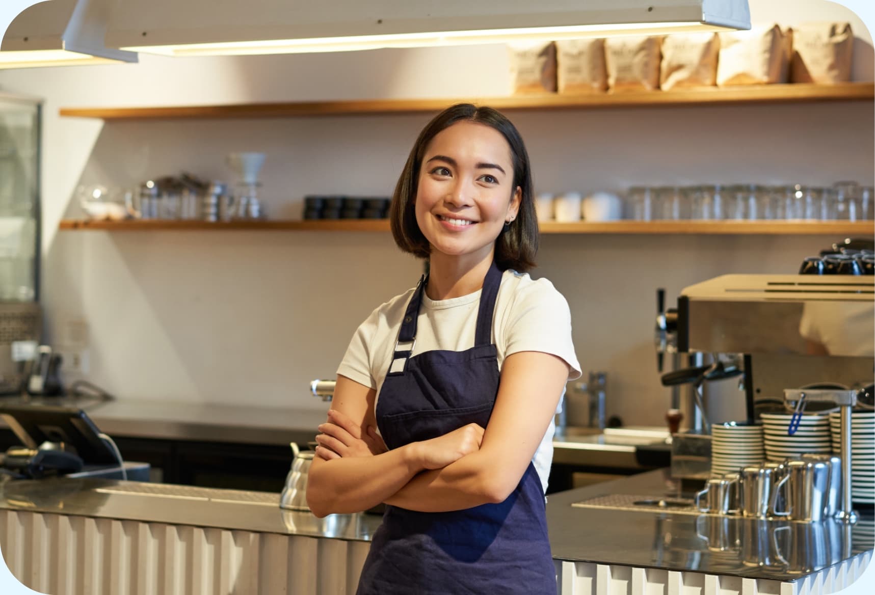 Cafe owner smiling behind the counter of an independent coffee shop